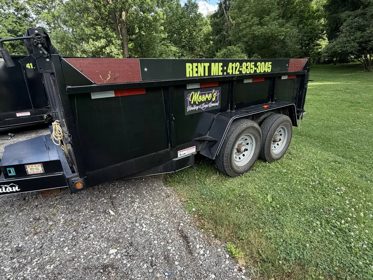 Moore's 8-yard black dump trailer with a Rent Me phone decal
